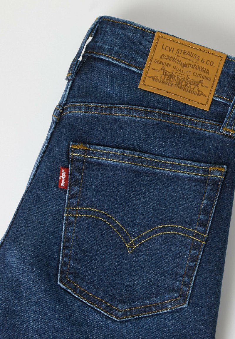 Poche arrière d'un jean Levi's bleu avec des coutures jaunes et un patch en cuir marron Levi Strauss & Co. sur la ceinture.