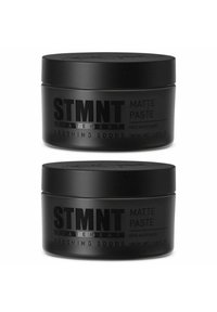 Two black, matte jars of STMTNT Matte Paste, each 100 ml, labeled clearly with product and brand information in bold gray text.