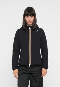 Giacca nera con cappuccio e cerniera frontale, caratterizzata da strisce gialle e bianche. Realizzata in un materiale liscio e leggero. Visibili più tasche.
