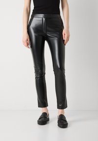 Musta nahkahousut, joissa on slim fit -malli, korkea vyötärö, etuvetoketjukiinnitys ja koristeelliset kultasävyiset nappikoristeet.