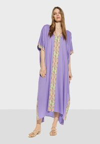 Lavendelfärgad kaftan med sidöppningar, präglad av en färgglad mönstrad trim längs framdelen och ärmarna, tillverkad av lättviktigt tyg.