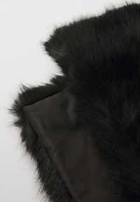 Black faux fur fabric with long, soft strands, contrasted by a sleek black satin backing. Textured edges create a rich visual contrast.