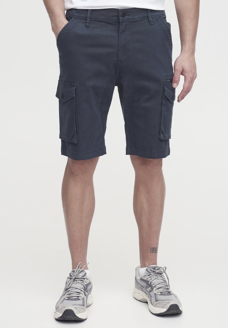 Marine Cargo-Shorts aus robustem Material, mit zwei seitlichen Taschen, flachem Bund und lockerer Passform. Detaillierte Nähte entlang des Saums.