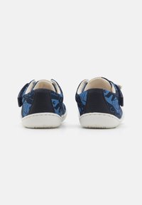 Scarpe in tessuto blu con un motivo floreale, dotate di un tacco in pelle blu scuro e una suola in gomma bianca. Fascetta regolabile per un'indossabilità facile.