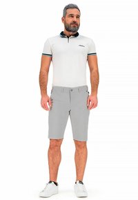 White polo shirt with a black collar and blue accents, paired with light gray shorts. Footwear is white sneakers. Clean, casual styling.