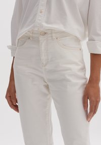 Vita jeans i denim med smal passform, utrustade med framfickor, subtila sömmar och knappstängning vid midjan. Slät textur.