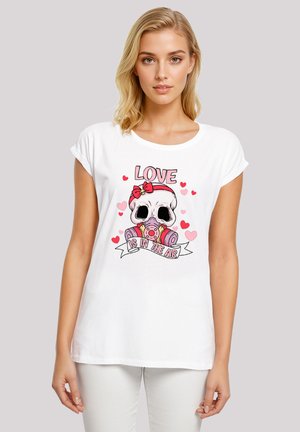 Weißes Baumwoll-T-Shirt mit einem bunten Grafikdesign eines Schädels mit einer Schleife, einer Kamera und dem Text "DIE LIEBE LIEGT IN DER LUFT", umgeben von Herzen.