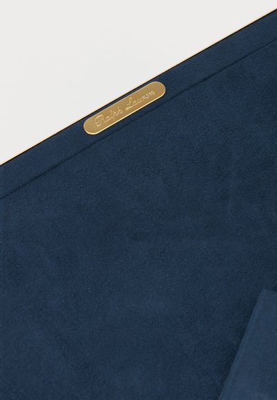 Μπλε ύφασμα με μια μικρή χρυσή μεταλλική ετικέτα χαραγμένη με τη φράση "Ralph Lauren" κατά μήκος της άκρης σε λευκό φόντο.