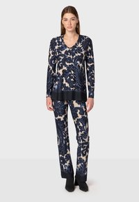 Set di top a maniche lunghe con scollo a V e pantaloni in un motivo floreale blu navy e crema. Il tessuto è morbido con un bordo nero a contrasto all'orlo e ai polsini.