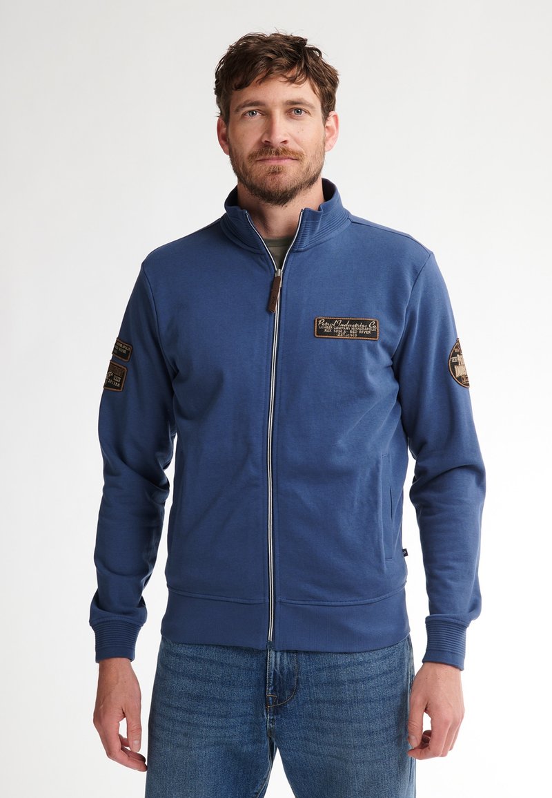 Felpa blu con zip e colletto alto, caratterizzata da toppe marroni sulle spalle, polsini a coste e un tessuto testurizzato.