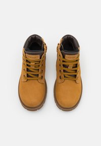 Botas de tobillo de cuero marrón claro con acentos marrones, que presentan cordones redondos, un cuello acolchado en el tobillo y una suela de goma texturizada.