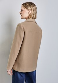 Kamelfärgad ullblandad kappa med krage, strukturerade axlar och långa ärmar, med rak skärning och detaljerat bakstycke.
