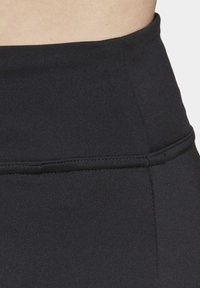 Højtaljede sorte leggings lavet af glat, strækbart stof. Dækker et syet taljebånd og sømløs tekstur.