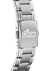 Nerūdijančio plieno laikrodis su šlifuotu paviršiumi, turintis kvadratinį užsegimą, graveruotą "LOTUS". Apyrankė turi tarpusavyje vienas su kitu susijungiančius saitelius.