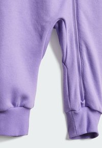 Lila pulóver anyag ribbed mandzsettákkal és oldalzsebekkel, a varrás mentén zipzárral. Puha textúra és laza stílus.