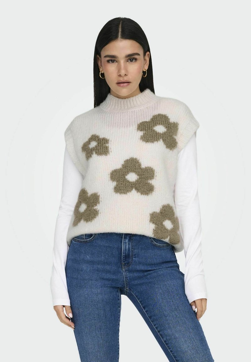 Ärmelloser Strickpullover mit hohem Kragen, verziert mit pastellrosa und olivgrünen Blumenmustern, getragen über einem langärmeligen weißen Oberteil.