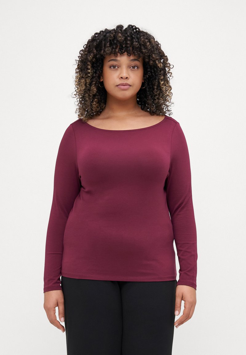 Burgundy long-sleeve top with a wide scoop neckline, made of soft fabric, featuring a fitted silhouette and smooth texture. Worn with black pants.