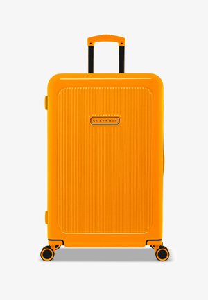 Harde koffer in feloranje. Heeft een verticale ribbelstructuur, zwarte handgreep en wielen. "SUITSUIT" logo aan de voorkant.