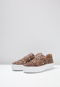 Leopardenmuster Slip-On-Schuhe mit einem strukturierten Obermaterial, goldenen Nieten und einer dicken weißen Gummisohle. Niedriges Profil-Design.