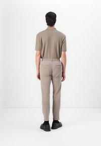 Brown short-sleeve polo shirt paired with light brown tapered pants and black shoes, featuring a relaxed fit and elastic waist.