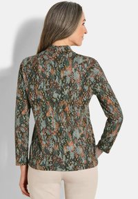 Langemouws shirt in groene, oranje en beige gestreepte stof. Beschikt over een hoge hals met een textuurontwerp en een getailleerde silhouet.