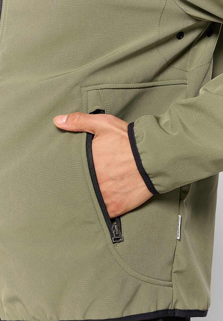 Veste olive avec une texture lisse, dotée d'une poche zippée et de accents noirs autour des poignets et de l'ourlet.