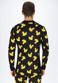 Long-sleeve shirt in a black stretch fabric featuring a repeated pattern of yellow rubber ducks with red beaks. Smooth texture, fitted design.