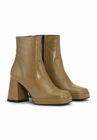 Tan krāsas ādas potītes zābaki ar gludu tekstūru, ar masīvu bloku papēdi, sānu rāvējslēdzēju un noapaļotu purngalu.