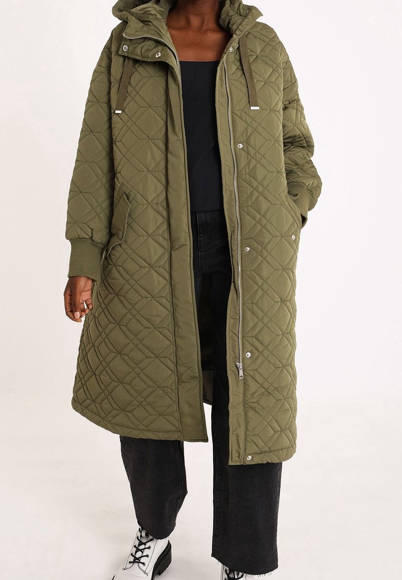 Olijfgroene gewatteerde lange jas met een capuchon, ritssluiting en zijzakken; heeft ribgebreide manchetten en een gestructureerde afwerking.