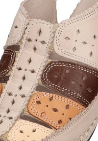 Sandalias de cuero con patrones de diamante recortados. Los colores incluyen beige claro, marrón y melocotón, con costuras contrastantes y texturas suaves.