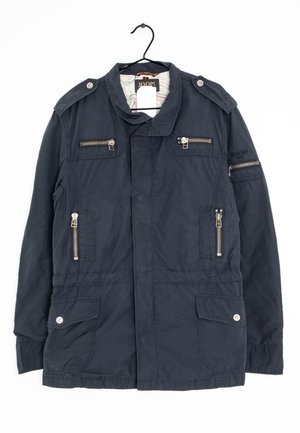 Chaqueta de marina hecha de tela, con cremalleras en el pecho y las mangas, epaulettes en los hombros, dos bolsillos frontales y un botón a presión en el dobladillo.