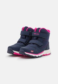 Bottes imperméables bleu foncé avec des accents roses, sangles velcro, semelle texturée et un petit emblème de drapeau. Conçues pour la durabilité et le confort.
