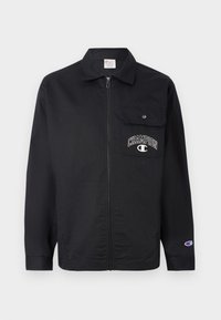 Svart zip-up jakke laget av slitesterk stoff. Har en brystlomme og "CHAMPION"-logo brodert på lommen. Lange ermer med mansjetter.