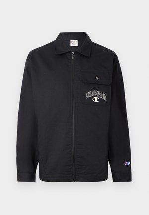 Svart zip-up jakke laget av slitesterk stoff. Har en brystlomme og "CHAMPION"-logo brodert på lommen. Lange ermer med mansjetter.