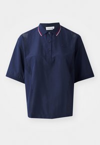 Polo shirt navy blue a maniche corte con chiusura a bottone, colletto a contrasto con dettagli rossi e bianchi, e pannelli laterali perforati per una maggiore traspirabilità.