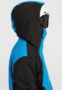 Chaqueta de esquí azul y negra con capucha, que presenta una textura suave, una cremallera resistente y un diseño en bloques de color contrastantes.