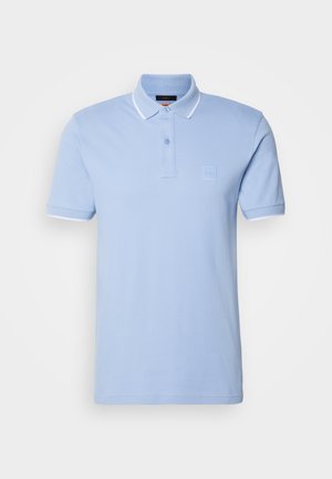 Heled sinine puuvillane polo särk. Omab kolme nupuga nööpse sulgemist, soonikkoes kaelust ja valgeid aksente varrukatel. Logo teip rindel.