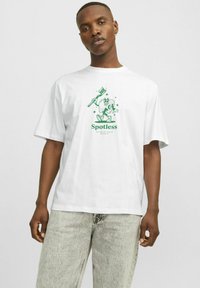 Tricou alb supradimensionat cu o ilustrație grafică verde a unui personaj cu o periuță de dinți, textul "Fără pete" și un design confortabil.