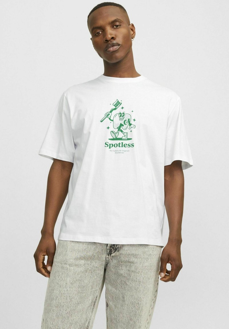 Tricou alb supradimensionat cu o ilustrație grafică verde a unui personaj cu o periuță de dinți, textul "Fără pete" și un design confortabil.