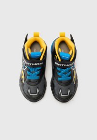 Sorte og grå sneakers med gule detaljer, blå snøringer og et Batman-logo. Har en polstret krave og teksturert gummisåle.