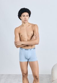 Ανοιχτό μπλε μπόξερ με μαύρο λογότυπο Nike στη μέση. Το υλικό φαίνεται ελαστικό, με εφαρμοστή σχεδίαση και ομαλή υφή.