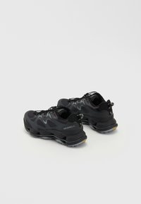 Schwarze Sportschuhe mit einem Obermaterial aus Mesh, gepolsteter Sohle und rutschfester Außensohle, grauen Akzenten und einer Schlaufe an der Ferse.