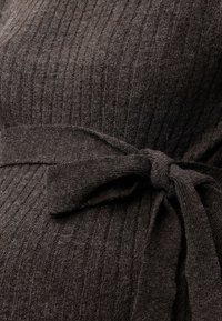 Tissu en maille côtelée brun foncé avec un nœud de ceinture noué autour de la taille.