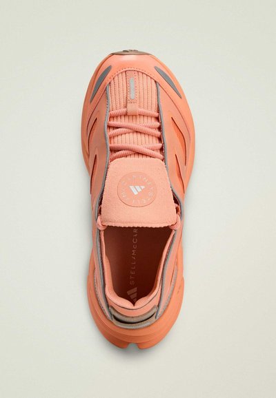 Baskets de sport roses avec une tige en tissu texturé, des accents réfléchissants et un bout arrondi. Dotées d'un logo sur la languette et d'une semelle à motif.