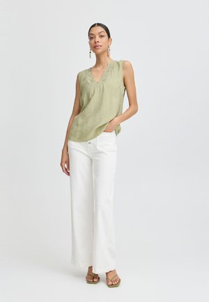 Haut sans manches vert olive avec un décolleté en V et des détails en dentelle. Associé à un pantalon large blanc et des sandales vertes. Design simple et décontracté.