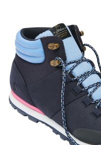 Botte de randonnée bleu marine avec col rembourré bleu clair, lacets noirs et bleus, œillets en laiton, bande médiane rose et étiquette de languette de marque.