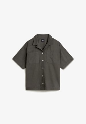 Chemise à manches courtes en tissu gris foncé. Dotée de deux poches poitrine, d'un col évasé et de boutons blancs à finition texturée.