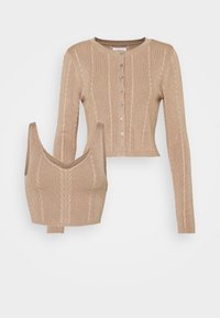 Ensemble beige en maille torsadée deux pièces avec cardigan court à boutons et top court sans manches à col en V assorti.