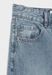 Světle modré džíny s běžným střihem, se přední kapsou a kontrastním prošitím podél švů.