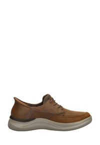 Zapato de cuero marrón con un acabado suave, suela gris claro, diseño con cordones, puntera redondeada y sutiles acentos texturizados en la parte superior.